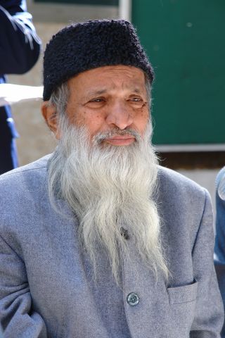 Abdul Sattar Edhi wearing a black cap and grey coat}