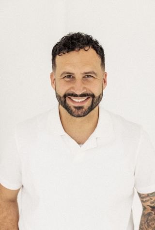 Mike Signorelli smiling in a white collared shirt against a white background}